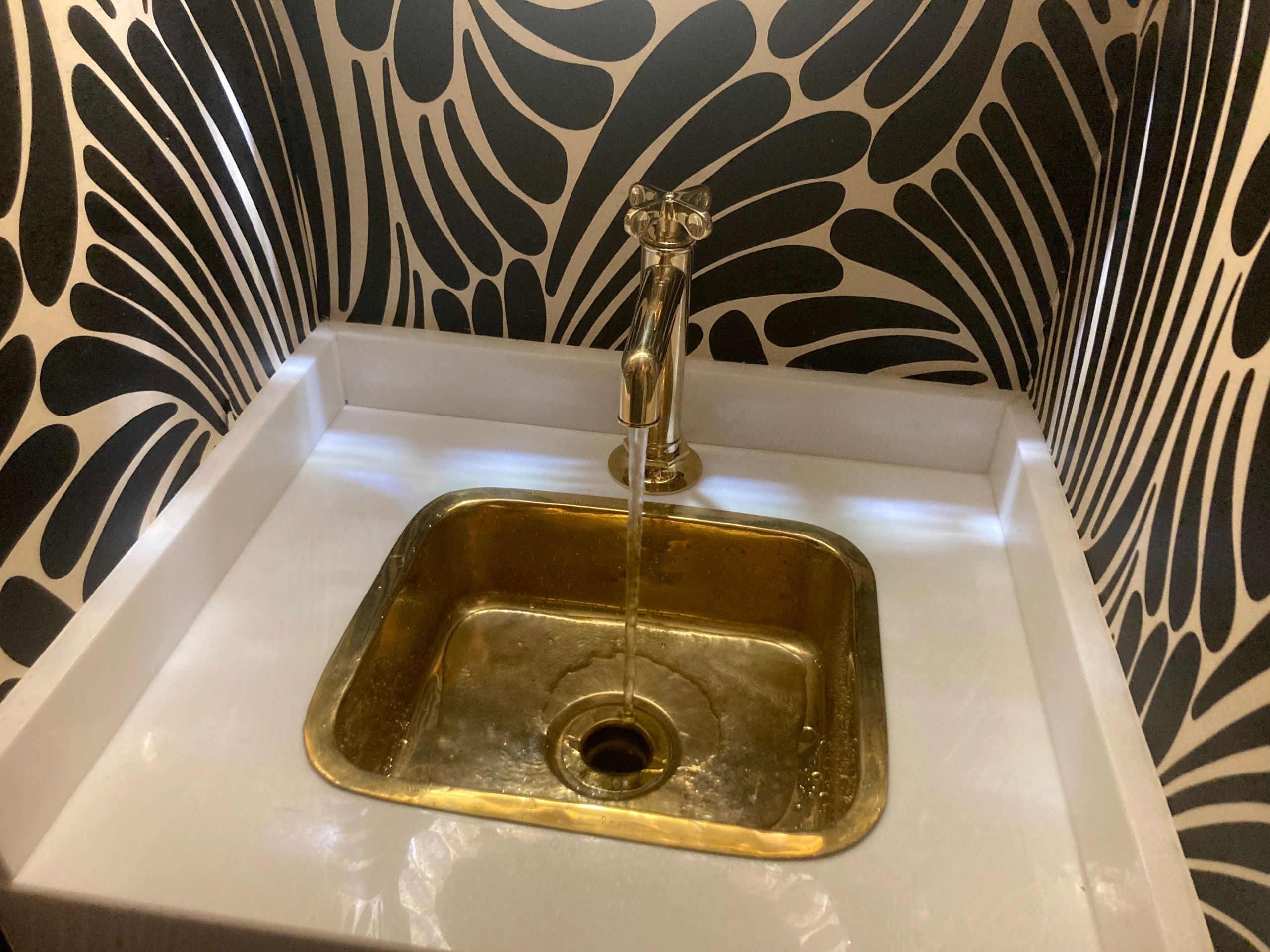Golden sink with patterned wallpaper