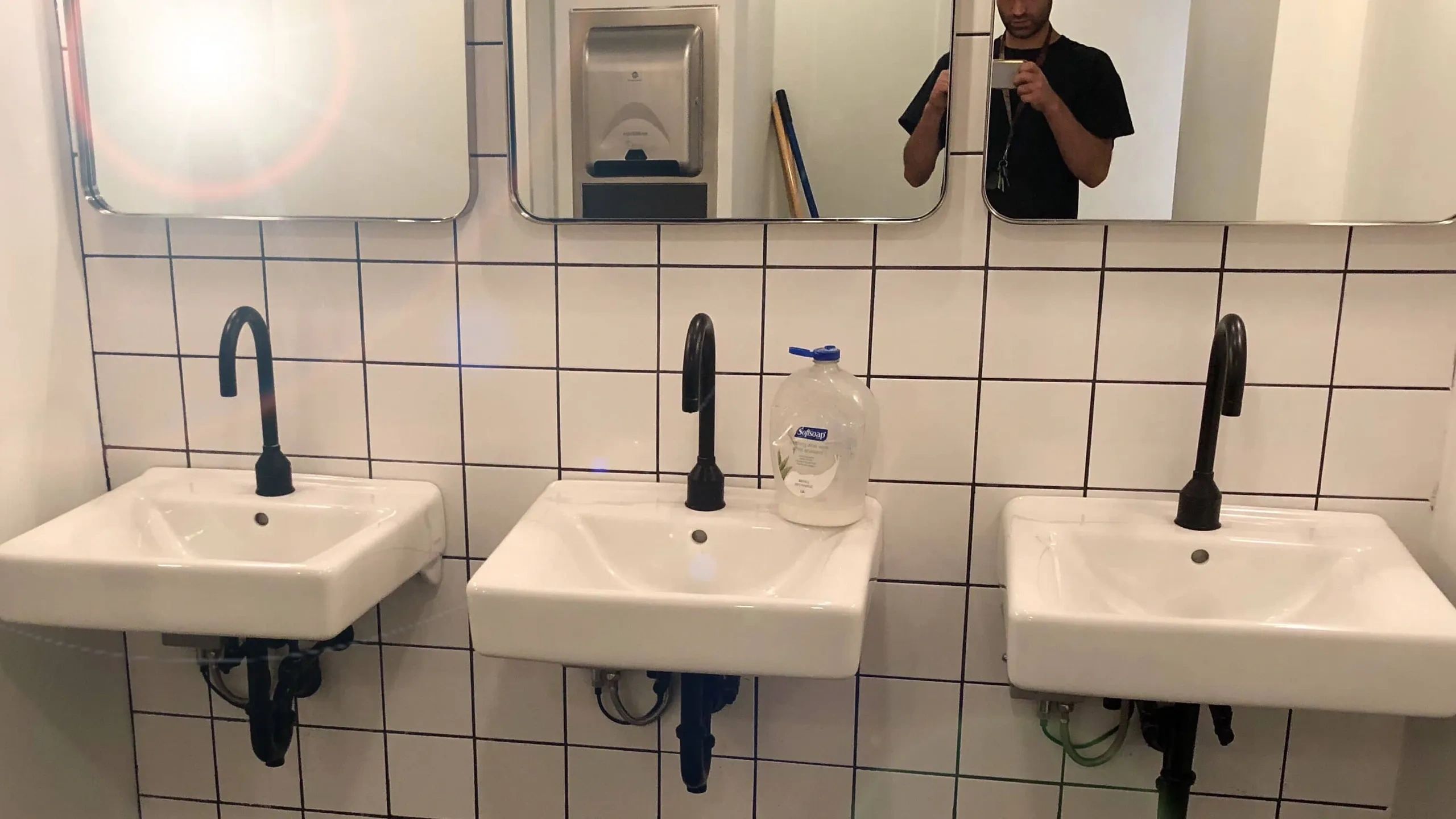 Three white sinks with black faucets