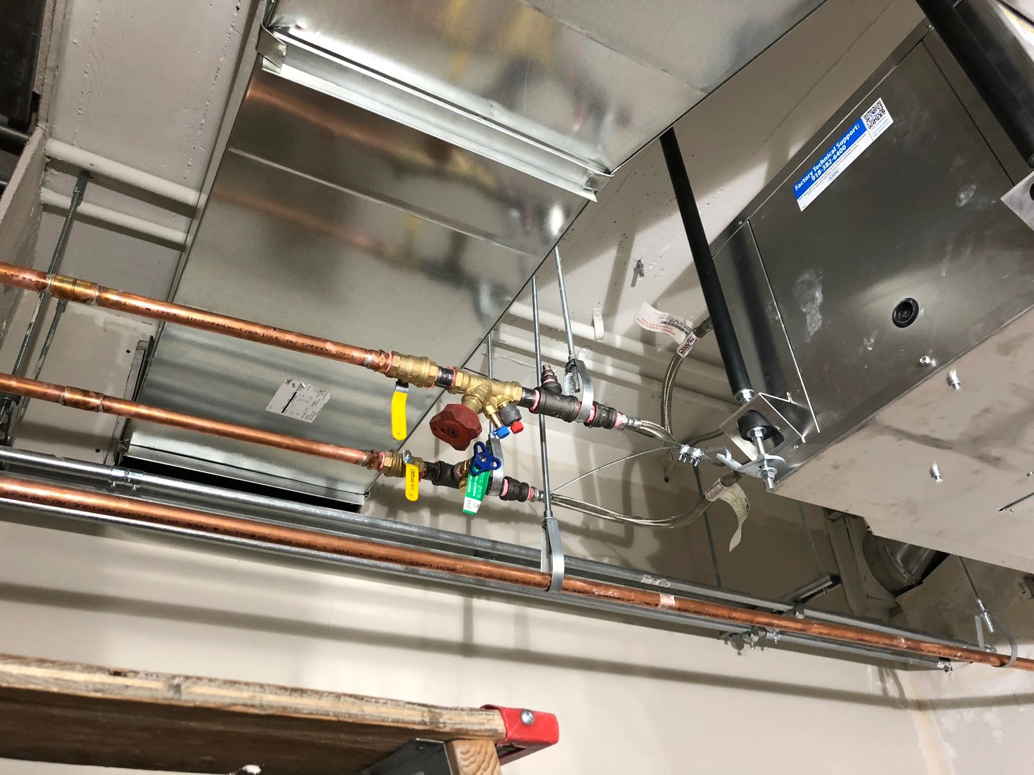 Copper pipes and HVAC ductwork above a ceiling